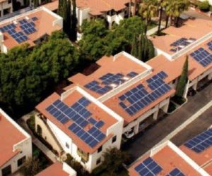 Aerial photograph of Solar Power Panels Installed on-top of a tiled roof houses.